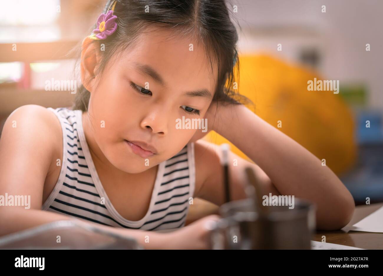 Portrait de l'asiatique belle fille d'enfant étudiant à la maison, gros plan de la fille assis à la table. Porte-crayons pour enfants, faites attention à l'écriture. Le c Banque D'Images