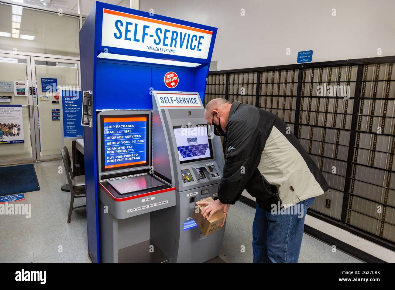 Un homme portant un masque scanne un colis au kiosque libre-service de la station Northwood du bureau de poste des États-Unis à fort Wayne, Indiana, États-Unis. Banque D'Images