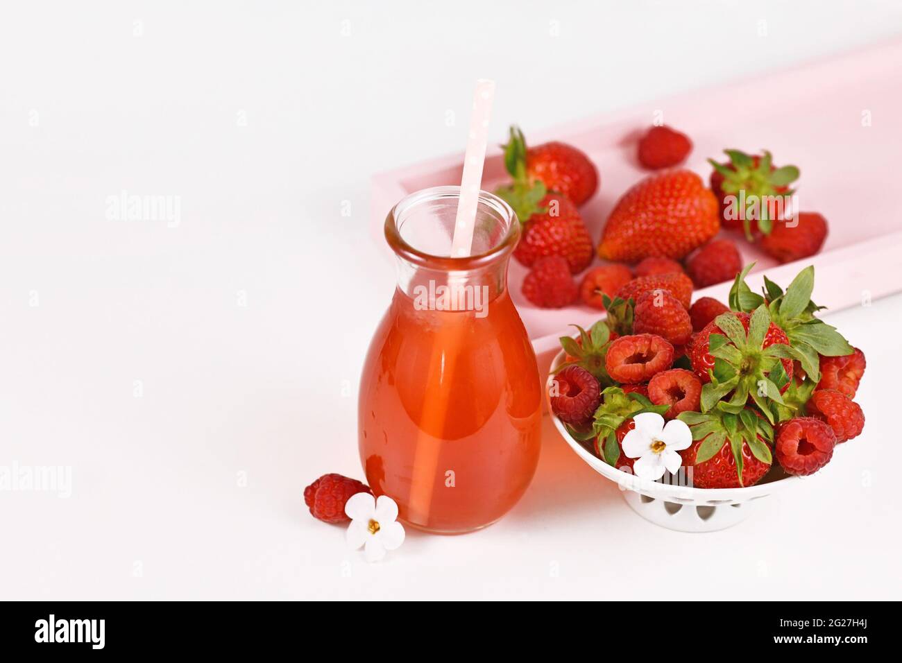 Limonade aux fraises rouges et aux framboises dans un pot entouré de baies Banque D'Images
