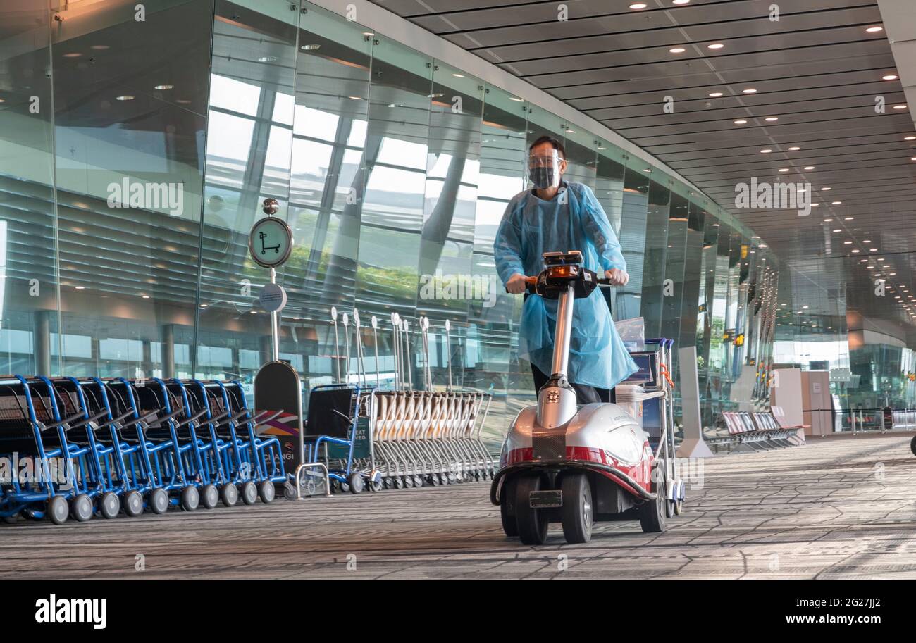 Singapour, le 8 juin 2021 - un employé de l'aéroport recueille des laissez-passer par un terminal de départ très calme à l'aéroport Changi de Singapour. Tout le personnel de l'aéroport porte des blouses de protection individuelle, des masques et des lunettes dans les terminaux d'arrivée et de départ. Avant la pandémie de Covd-19, en 2019, l'aéroport de Changi était le septième aéroport le plus occupé par le trafic international de passagers dans le monde et le troisième en Asie. Crédit : Rob Taggart/Alay Live News Banque D'Images