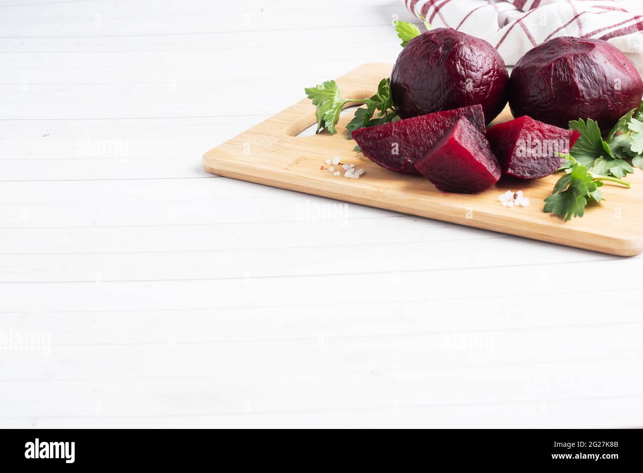 Betteraves bouillies entières et coupées sur une planche à découper avec des feuilles de persil sur fond blanc. Espace de copie, Banque D'Images Betteraves bouillies entières et coupées sur une planche à découper avec des feuilles de persil sur fond blanc. Espace de copie, Banque D'Images