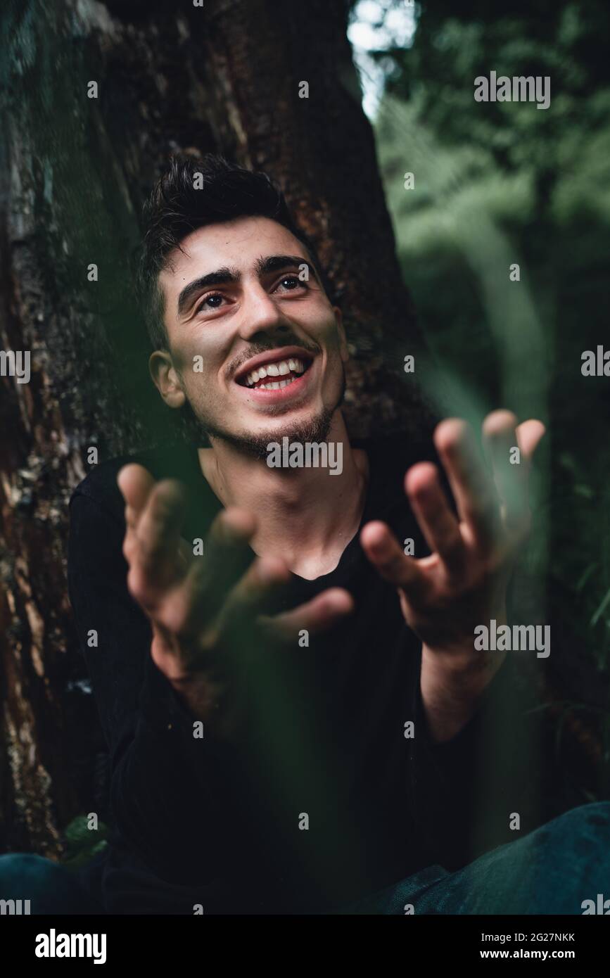 Le jeune homme qui penche sur un arbre dans la forêt demande pourquoi, la nature et le concept des gens Banque D'Images