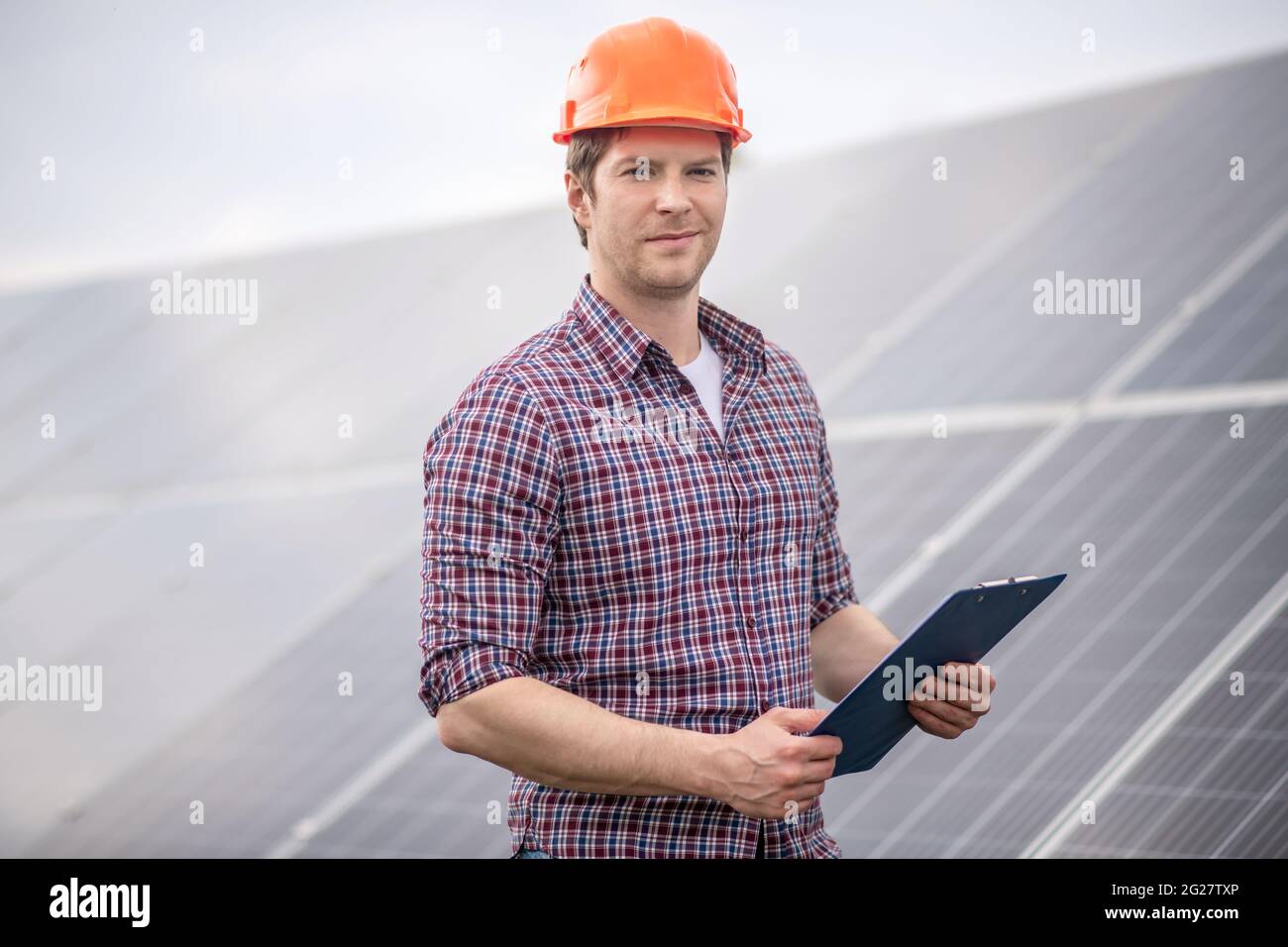 Homme dans un casque de protection avec des documents à proximité d'un objet Banque D'Images