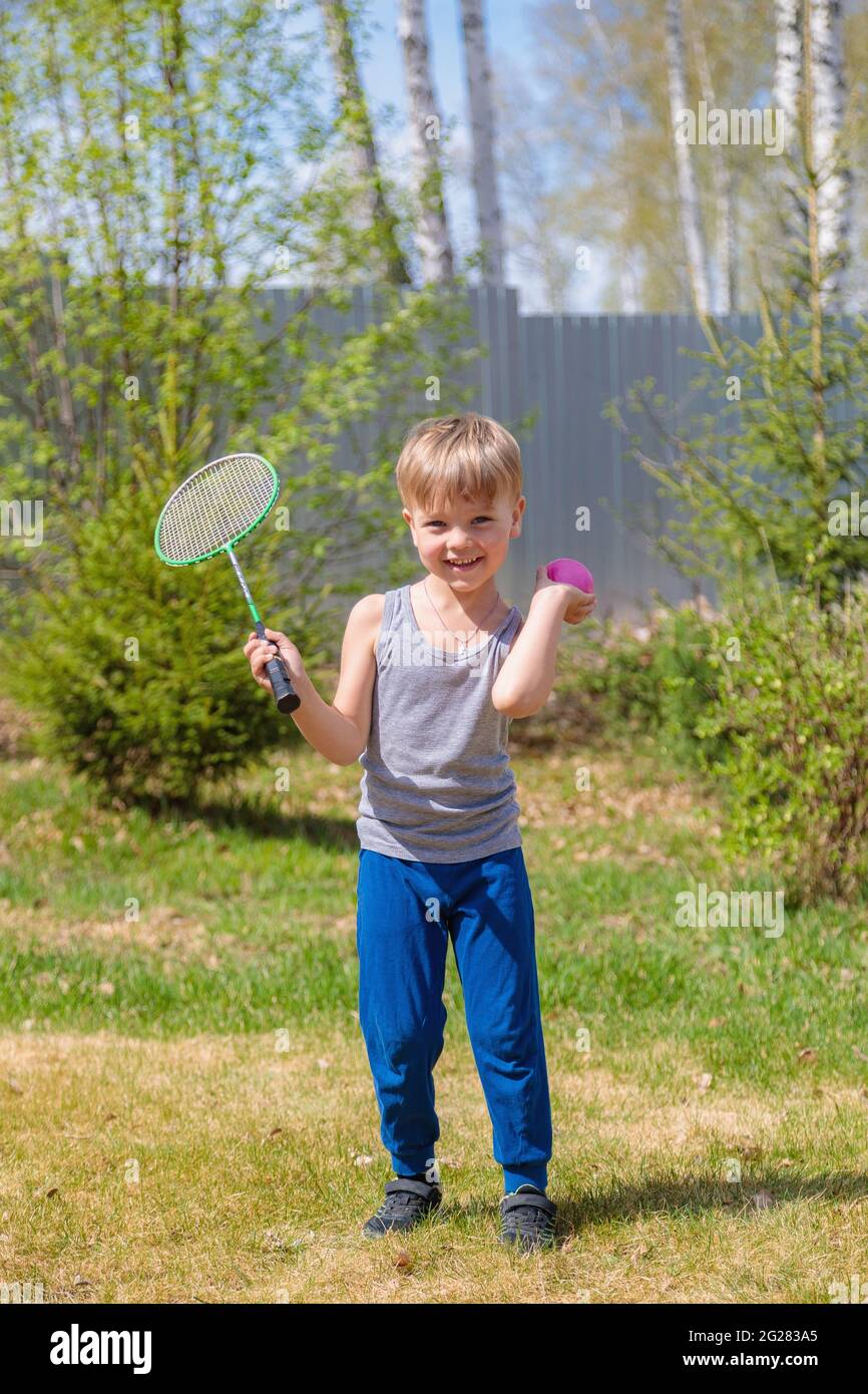 Un enfant aux cheveux justes joue du badbinton sur la pelouse. Banque D'Images