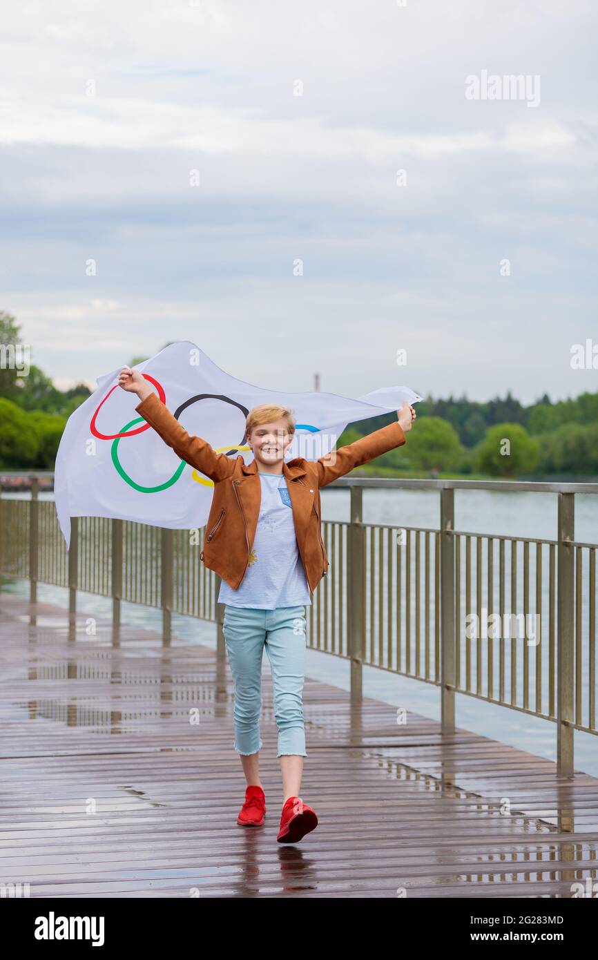 La blonde agitant le drapeau olympique à l'extérieur dans le parc. Jeux olympiques d'été. Moscou Russie 28 mai 2021 Banque D'Images