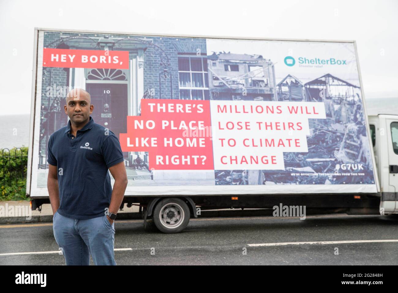 USAGE ÉDITORIAL SEUL Sanj Srikanthan, PDG de ShelterBox, avec une fourgonnette dotée d'un panneau publicitaire provocateur, lance la campagne « perte d'habitat humain » de ShelterBox à Falmouth, qui invite les dirigeants avant leur arrivée à Cornwall pour le Sommet du G7 à trouver des solutions globales à la crise climatique. Date de la photo: Mercredi 9 juin 2021. Banque D'Images