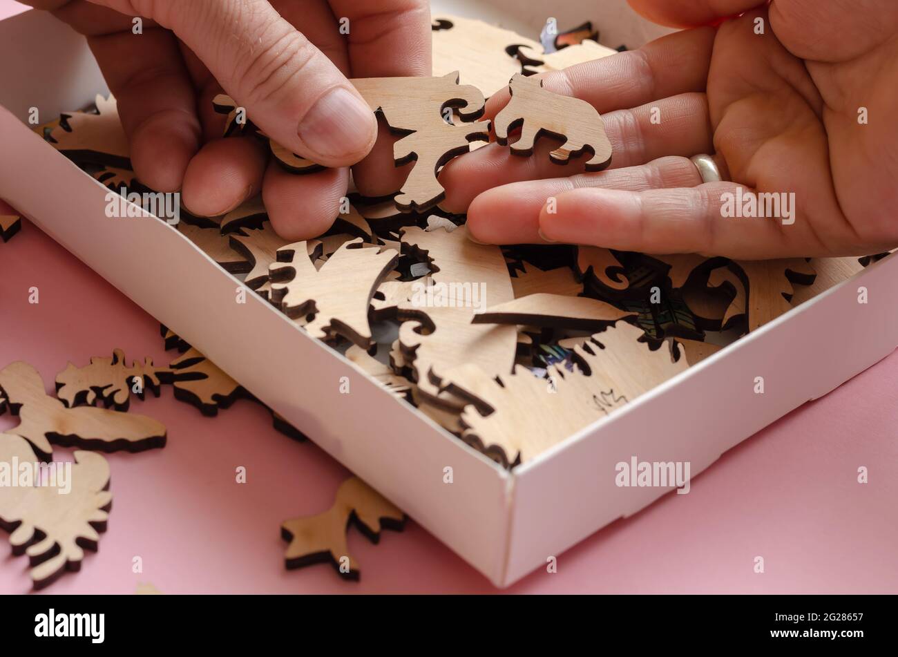 Une boîte ouverte avec un puzzle en bois gros plan. Homme et femme adultes  choisissant une pièce d'un puzzle compliqué. Loisirs actifs. Jeux logiques.  Sélectif Photo Stock - Alamy