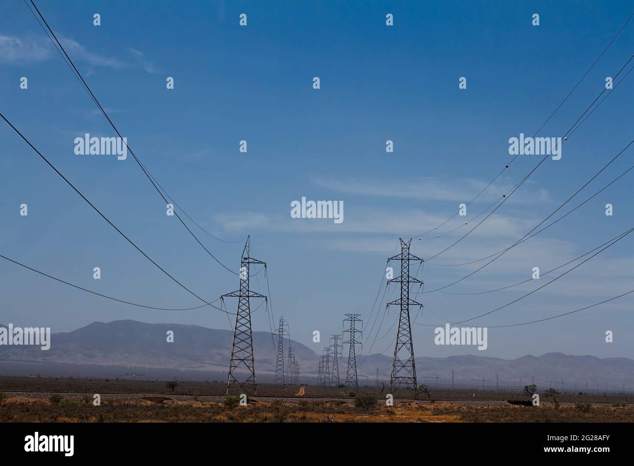 Deux lignes électriques haute tension et tours apportent de l'électricité à la ville industrielle de Port Augusta, en Australie méridionale, avec la fumée provenant des feux de brousse Banque D'Images