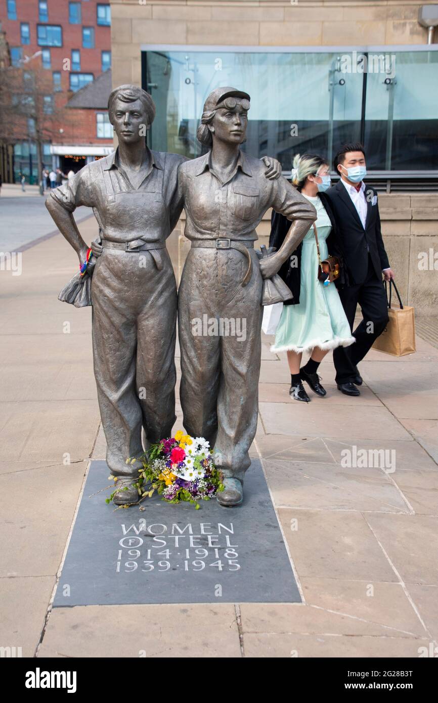 Sheffield UK: 17 avril 2021: La statue des femmes d'acier et un couple passant portant des masques tandis que Sheffield rouvre après la pandémie à Barkers Pool Banque D'Images