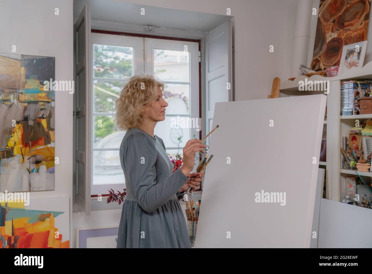 Une femme artiste de dessins, se préparant à créer une image créative, en face d'elle est une toile vierge. Copier l'épice. Dans l'atelier de la galerie. Banque D'Images