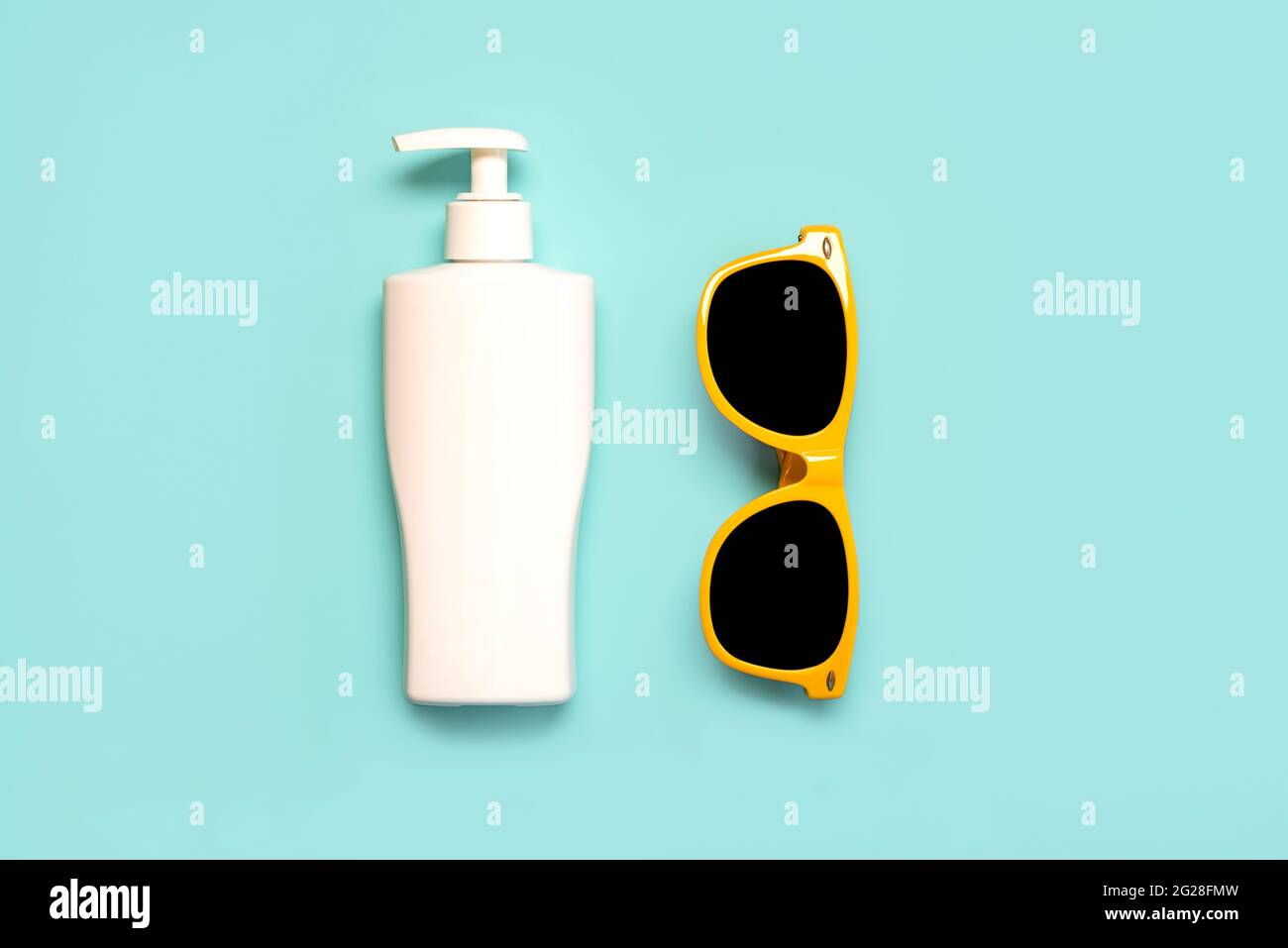 Concept de vacances d'été.vue du dessus des lunettes de soleil jaunes et une bouteille de crème solaire sur un fond bleu Banque D'Images