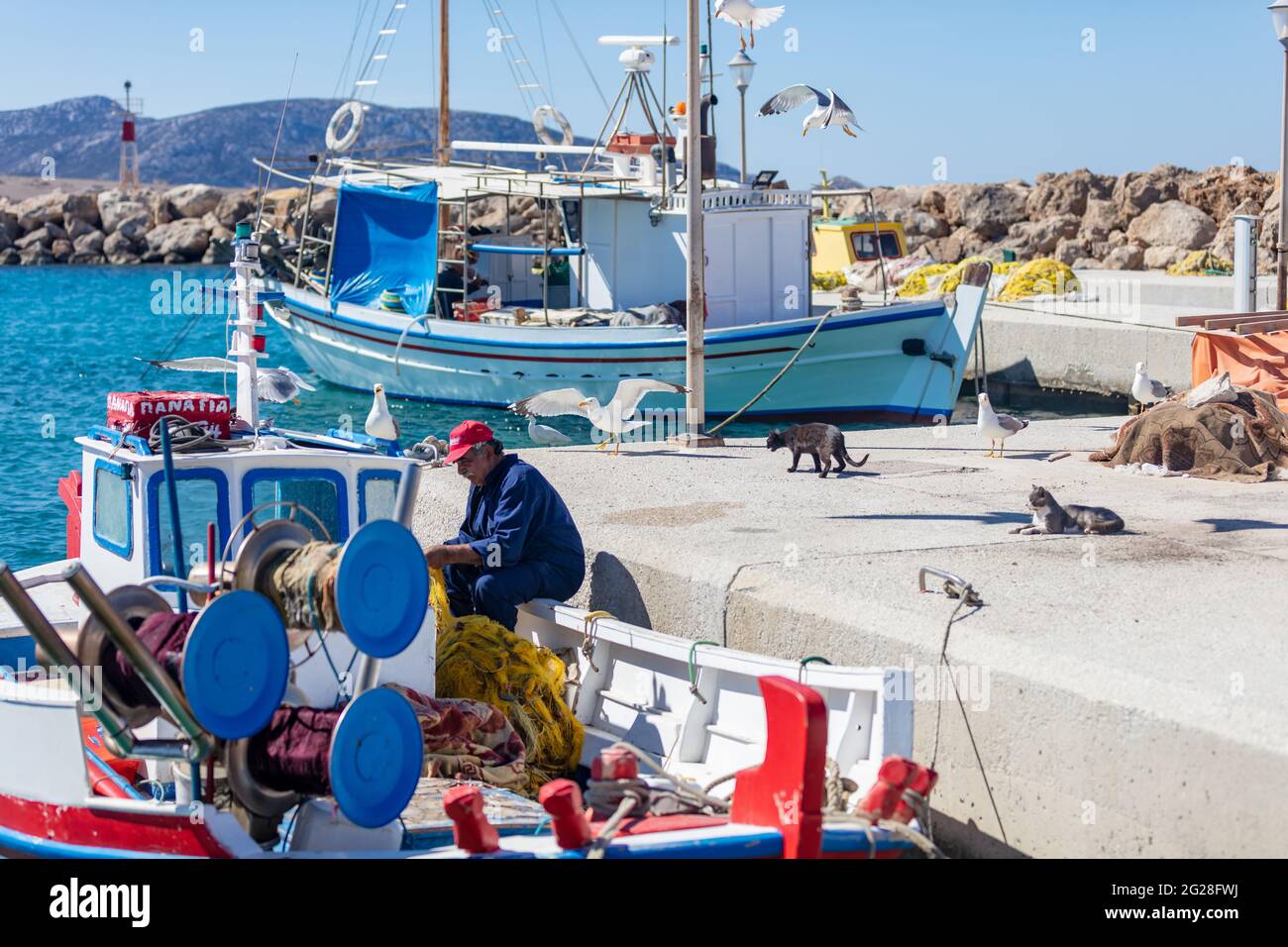 Grèce. Île de Koufonisi, Cyclades, 23 mai 2021. Scène de pêche Afetr au quai du port. Pêcheur travaillant avec les filets sur un bateau amarré, seagulls look Banque D'Images