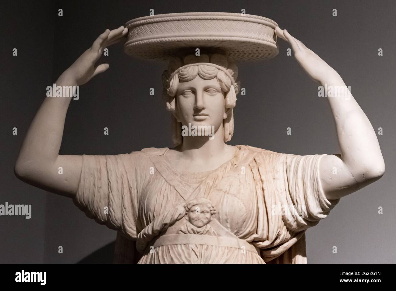 Gros plan sur l'ancienne statue romaine d'une femme portant un panier plat rond sur sa tête Banque D'Images