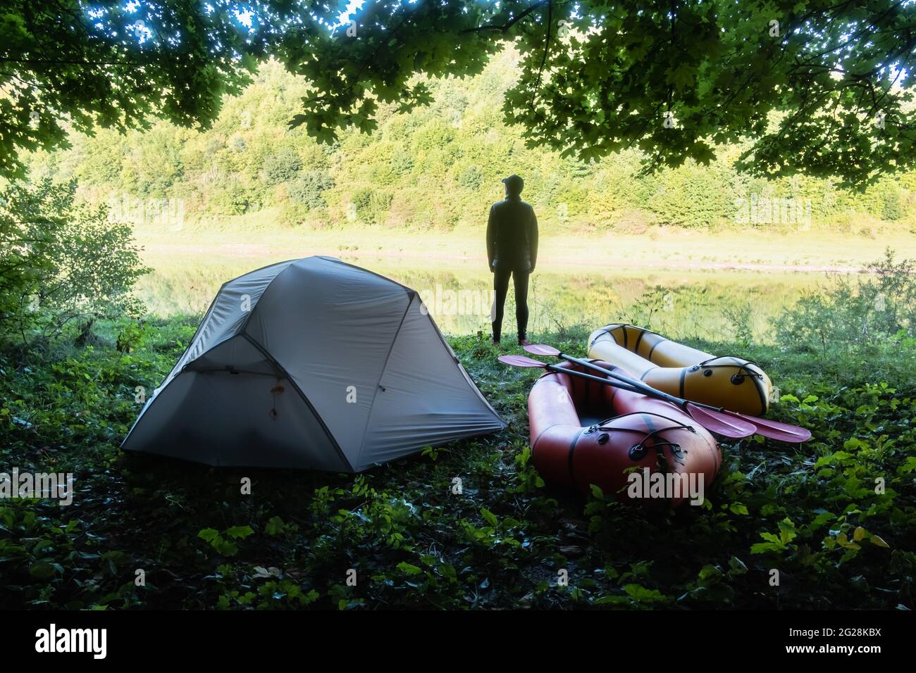 Homme près de la tente et des rabots dans le camp forestier près de la rivière. Packrafting. Concept de vie active Banque D'Images