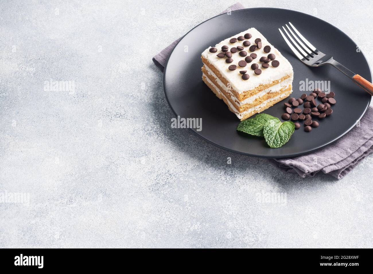 Génoise avec crème de beurre et morceaux de chocolat menthe sur une assiette noire. Dessert pour un événement de fête ou une fête d'anniversaire, vue du dessus, espace de copie. Banque D'Images Génoise avec crème de beurre et morceaux de chocolat menthe sur une assiette noire. Dessert pour un événement de fête ou une fête d'anniversaire, vue du dessus, espace de copie. Banque D'Images