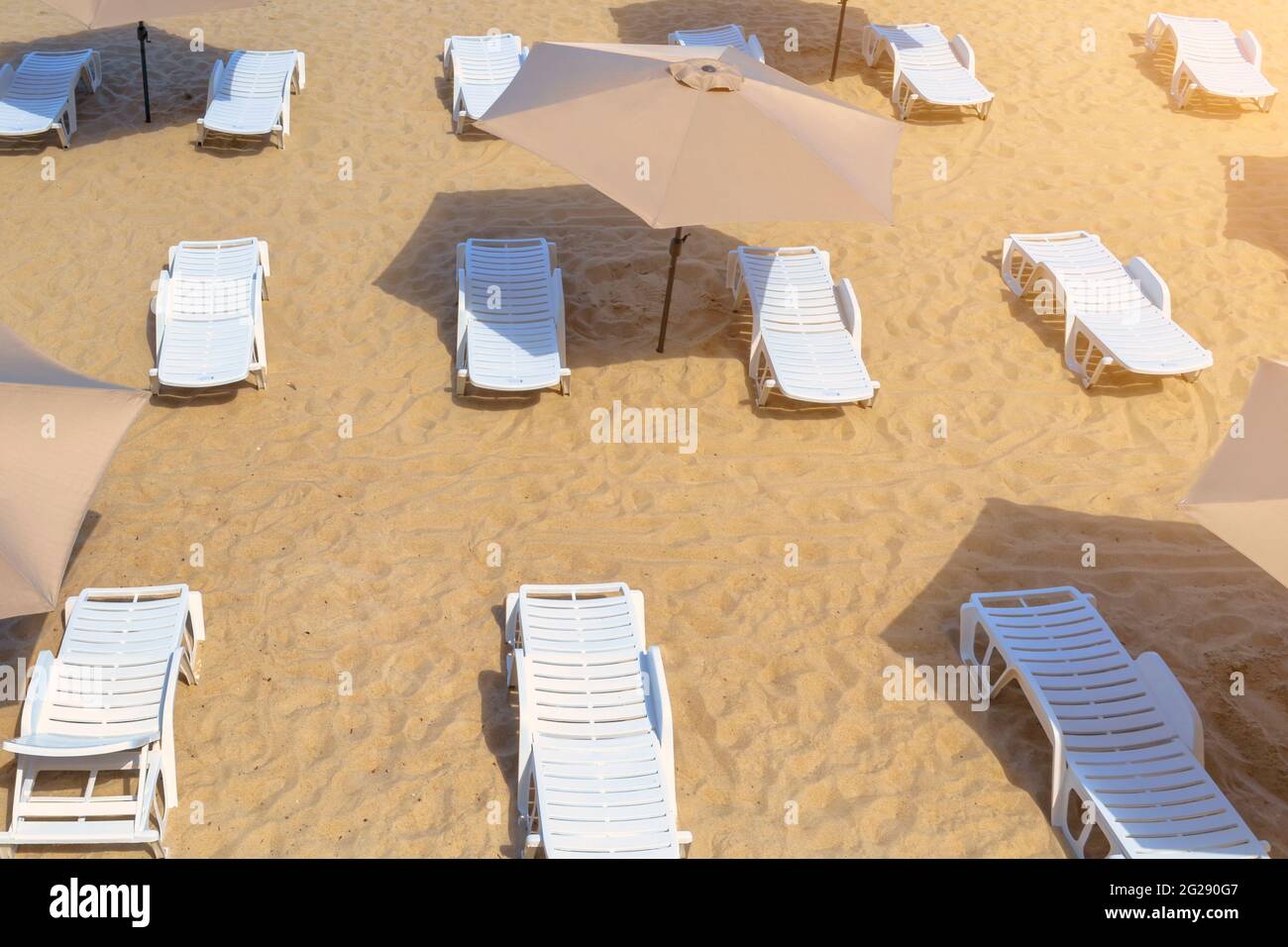 Chaises longues et parasols vides sur une plage de sable. Banque D'Images