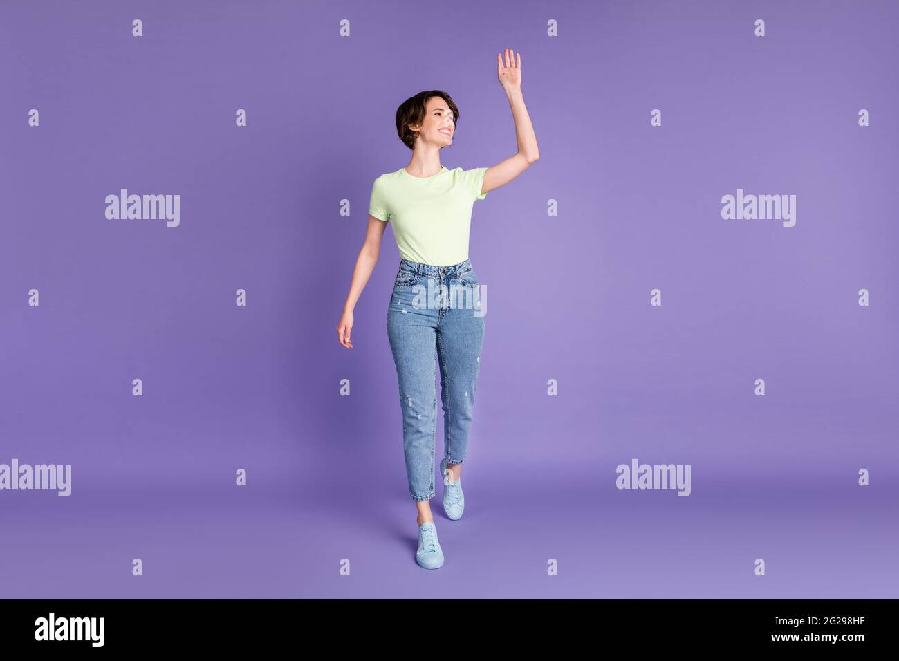 Vue sur toute la longueur du corps de fille attrayante de marche joyeuse salut bonjour isolé sur fond violet vif violet couleur violet Banque D'Images