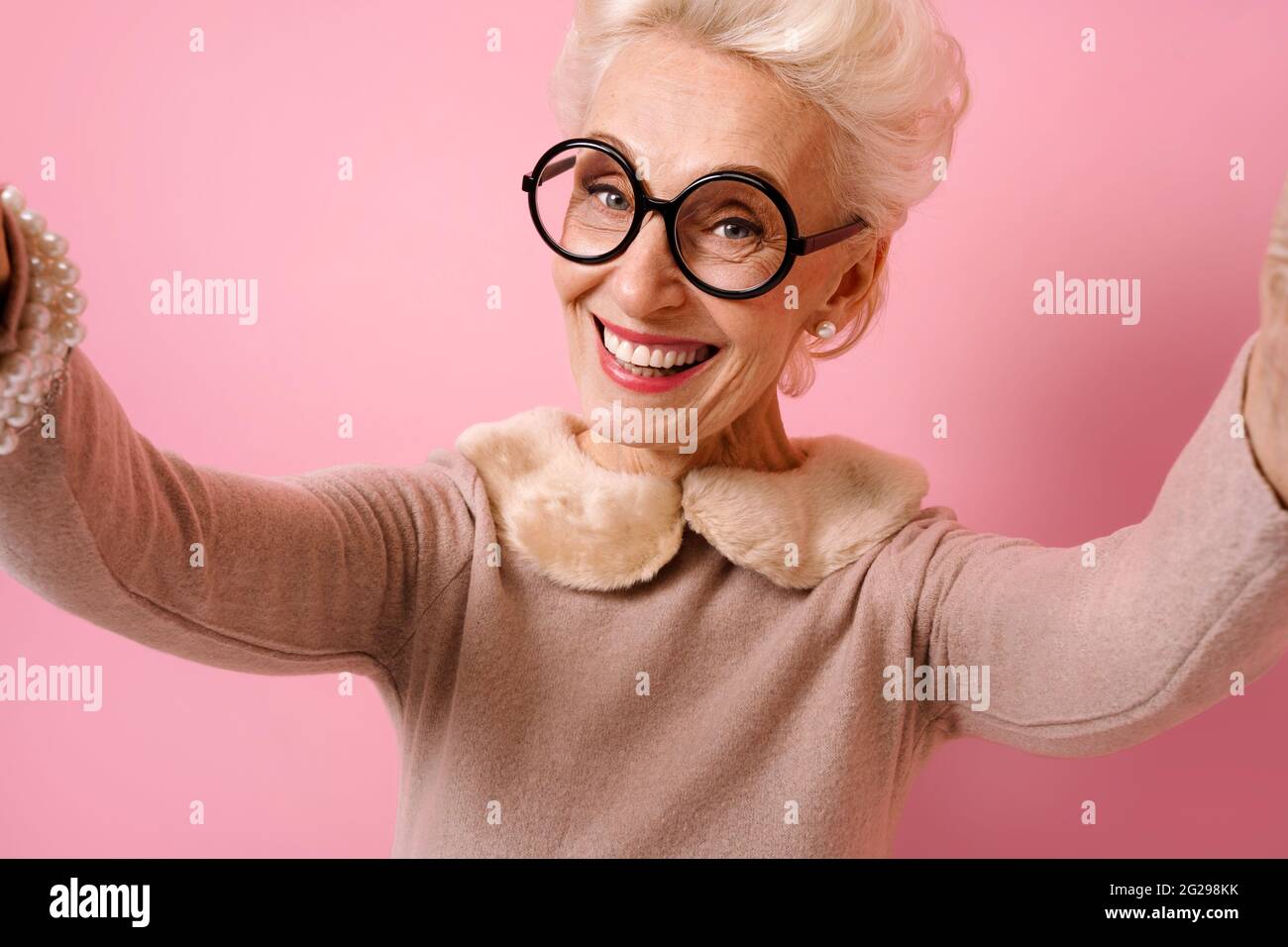 Grand-Mère Gaie Prenant Le Selfie Au Téléphone. Photo De Genre Femme Âgée  Porte Des Lunettes Sur Fond Rose Photo Stock - Alamy