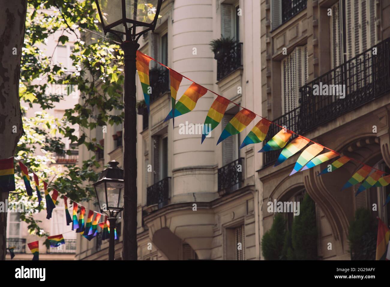 Décoration de bannières en forme de triangle dans les couleurs des drapeaux LGBTQ accrochés entre lanternes d'époque et maison en pierre ornée avec balcons. Gay Banque D'Images