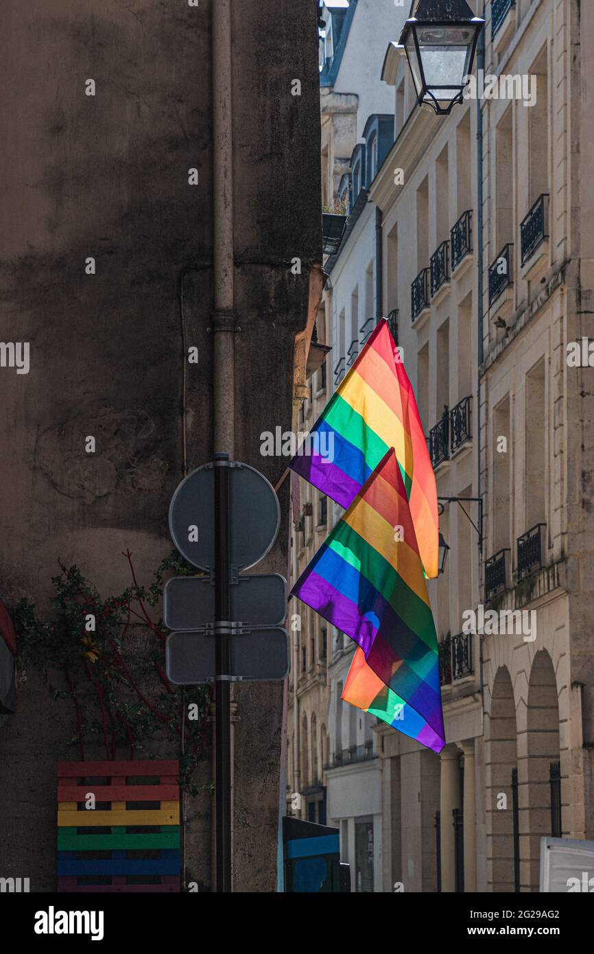 Drapeaux LGBTQ accrochés au coin du bâtiment historique pendant la fierté de Paris. Symbole de culture LGBTQIA. Lanterne d'époque, lampadaire et drapeaux gais éclatants Banque D'Images
