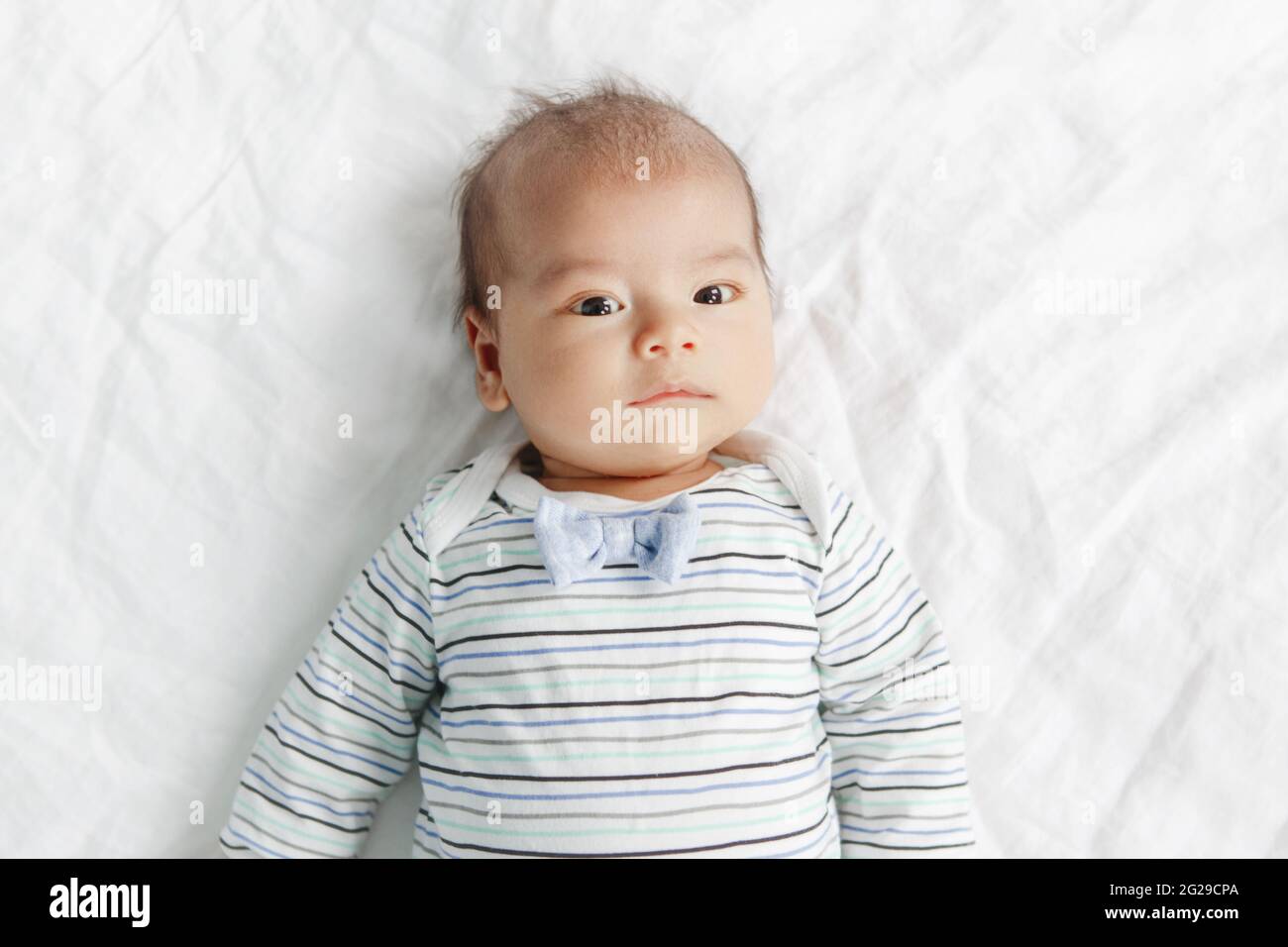 Deux mois nouveau-né asiatique chinois bébé garçon allongé sur son dos sur le lit. Banque D'Images