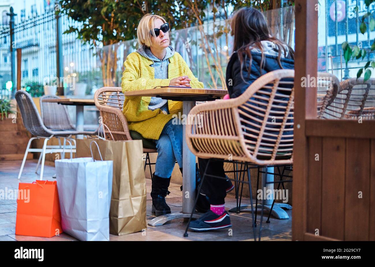 Une mère prenant un verre avec sa fille assise à la table du bar après avoir fait du shopping Banque D'Images