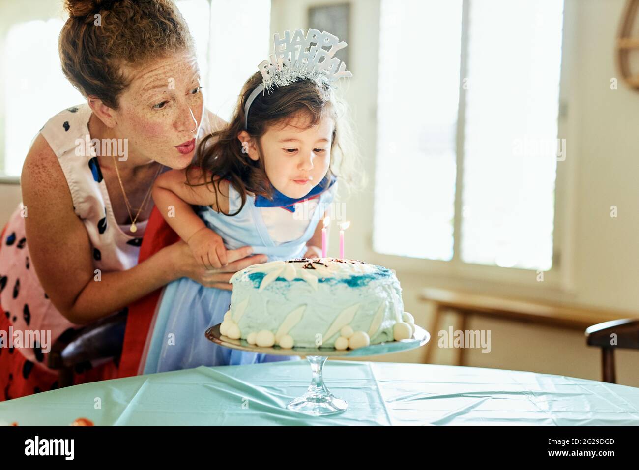 La Mere Et La Fille Soufflent Des Bougies Sur Le Gateau D Anniversaire A La Maison Photo Stock Alamy