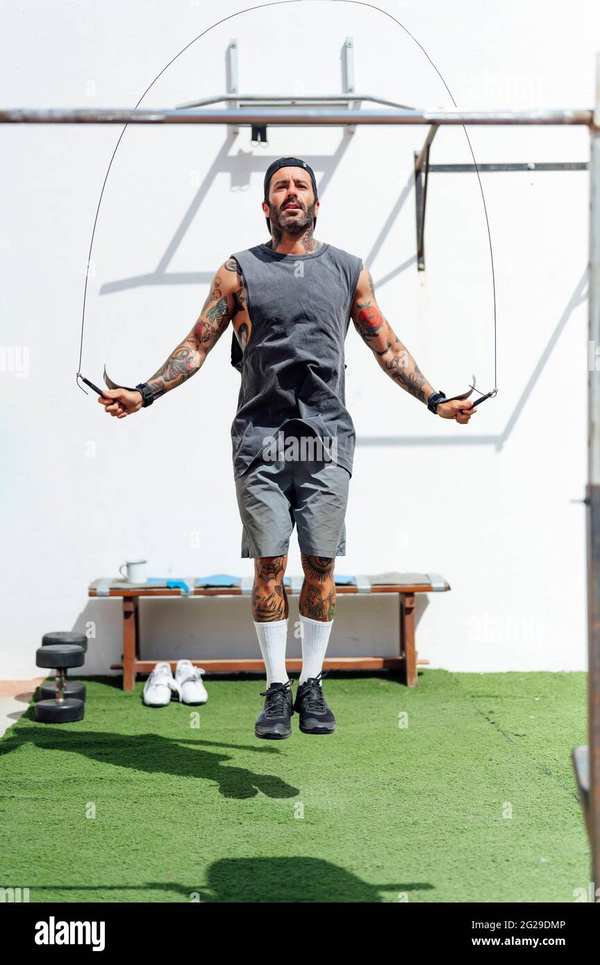 Un homme musclé sautant de l'exercice avec corde à sauter dans la salle de gym Banque D'Images