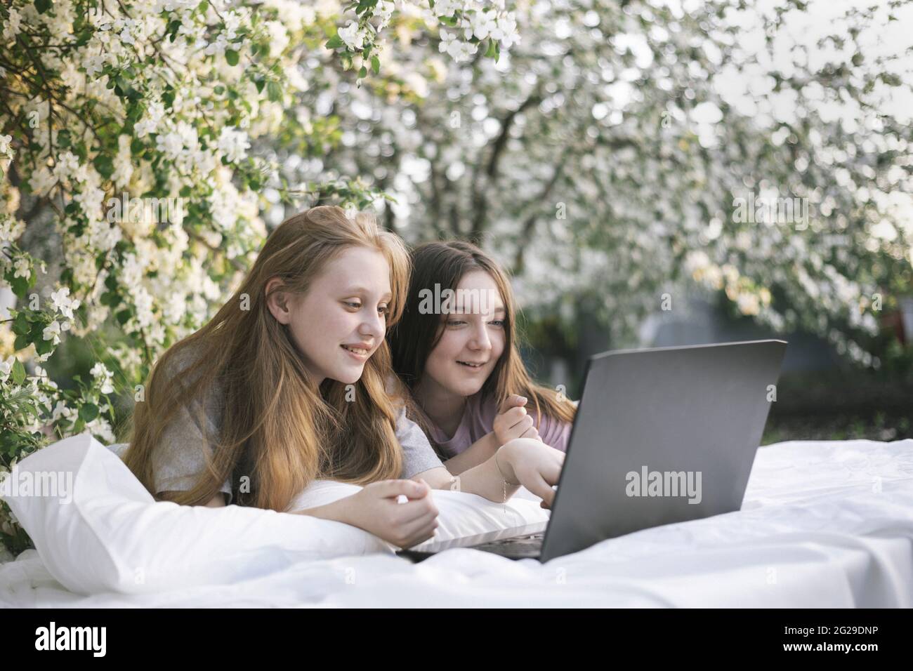 Grand angle d'adolescents regardant un ordinateur portable allongé sur le lit dans le jardin Banque D'Images