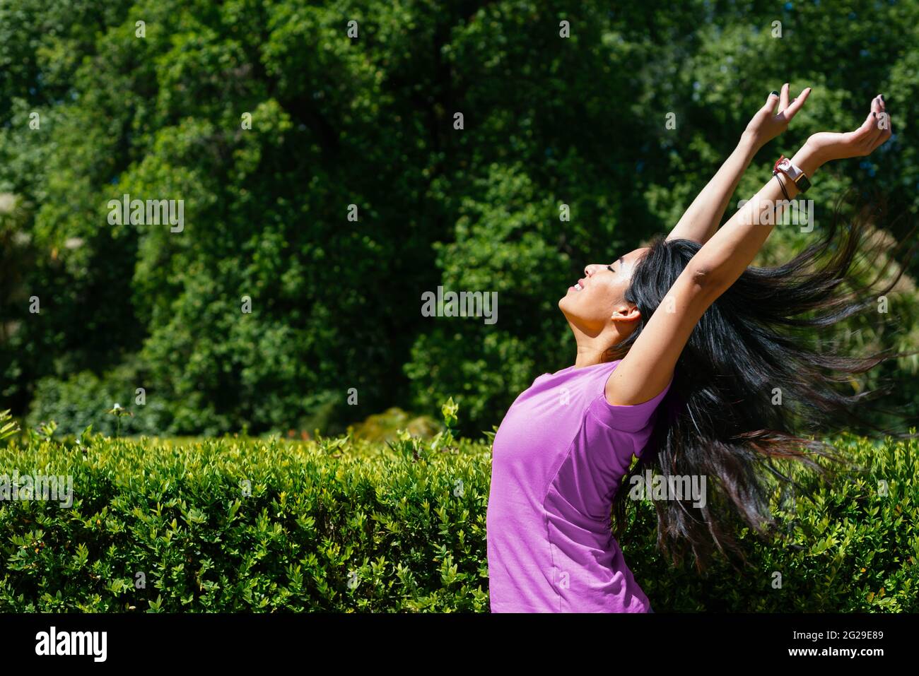 Jeune femme joyeuse dansant en plein air. Elle soulève ses bras en l'air. Banque D'Images