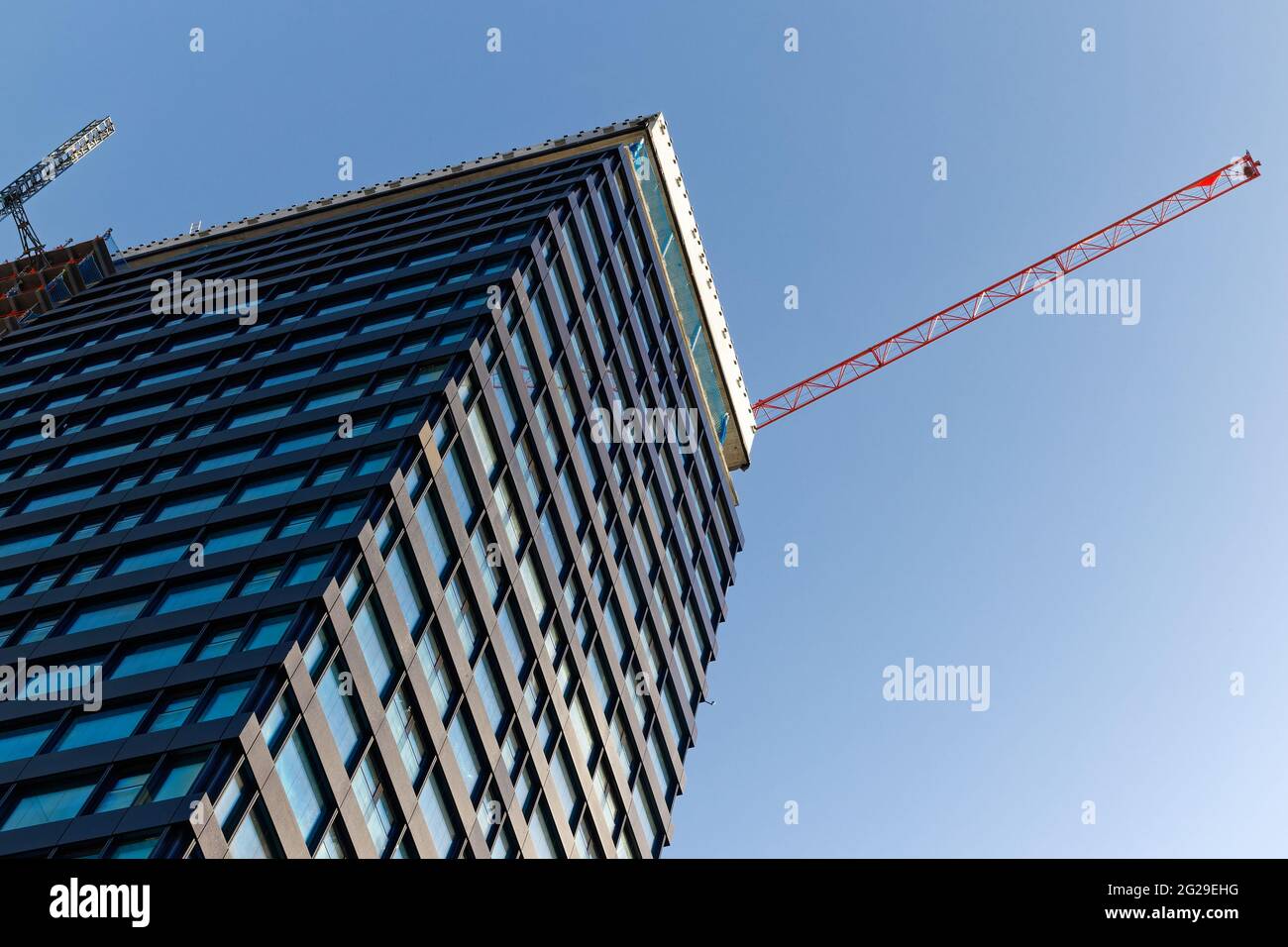 bâle suisse, 24 avril. 2021: grand gratte-ciel devant le ciel bleu avec grue de construction rouge, dans les grandes villes beaucoup de nouveaux bâtiments sont construits, par jour Banque D'Images