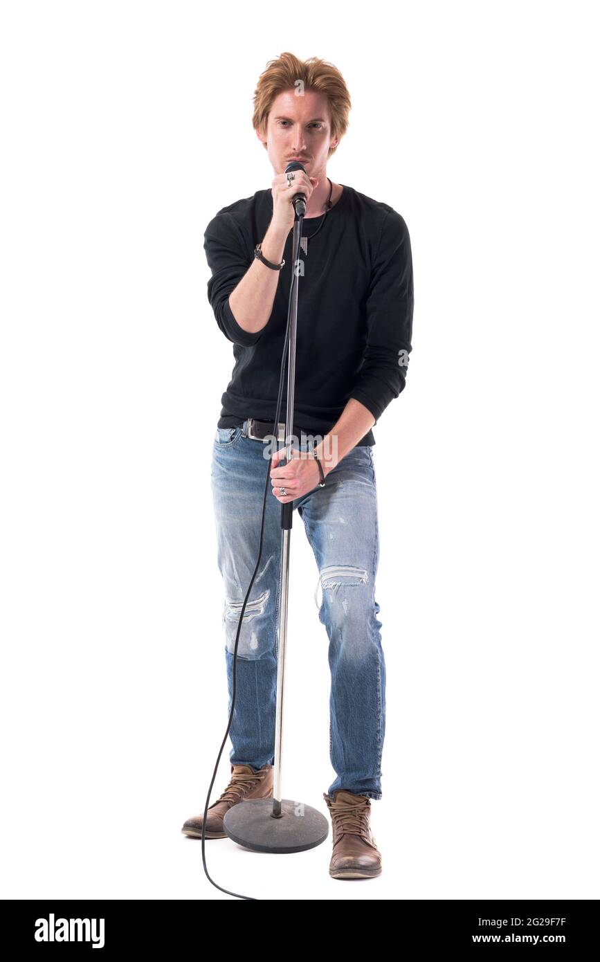 Cool jeune beau chanteur de musique rock mâle chantant sur le microphone regardant la caméra. Longueur totale du corps isolée sur fond blanc. Banque D'Images