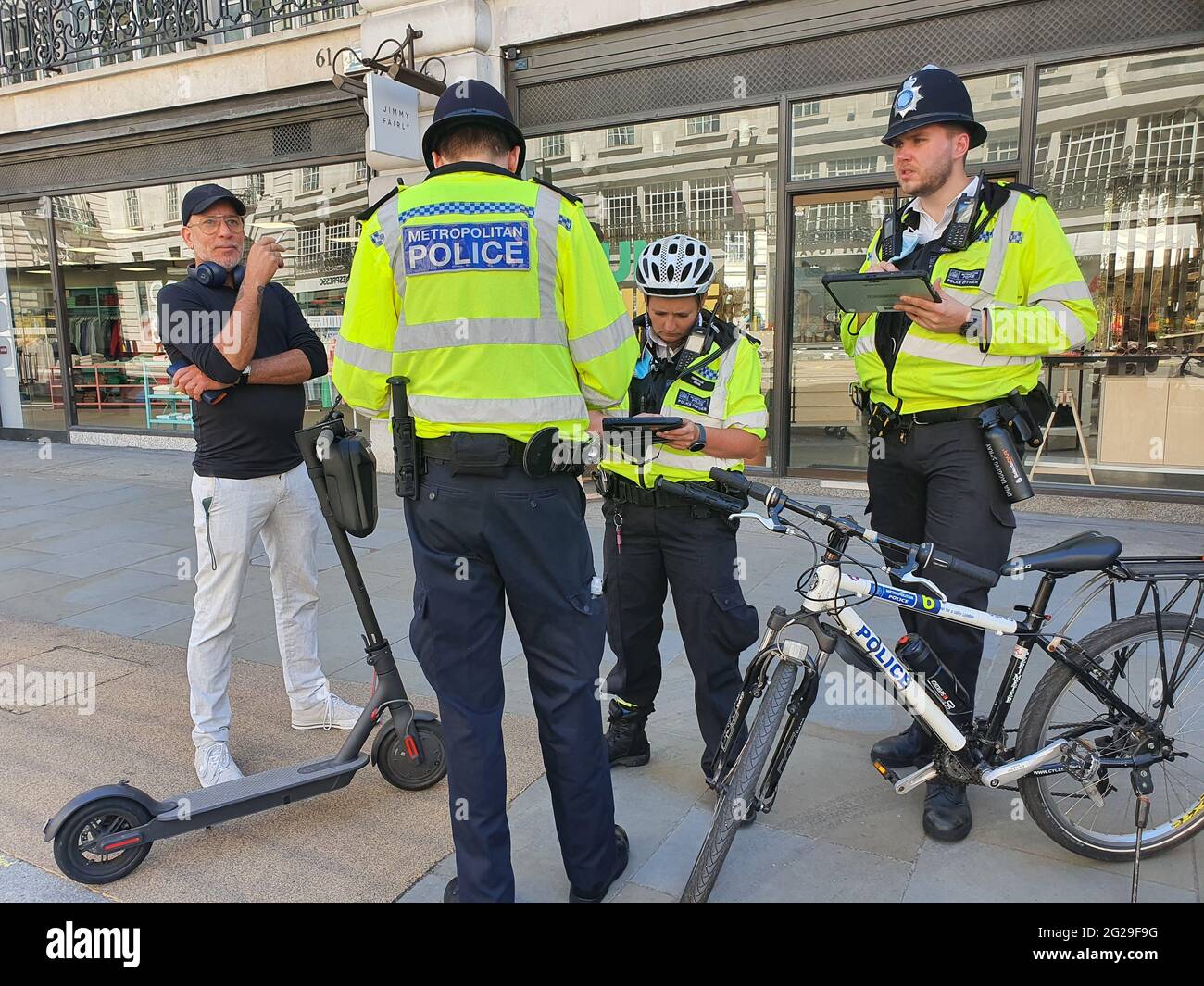 Londres, Royaume-Uni, 9 juin 2021: Police sur Regent Street fine personnes attrapé en utilisant des scooters électriques. Bien que certains arrondissements de Londres autorisent les essais de trottinettes électroniques, dans d'autres arrondissements, ils ne sont pas autorisés. Ils sont de plus en plus populaires en tant qu'option de transport vert, mais leur application est erratique et les règles sont déroutantes pour la plupart des gens. Anna Watson/Alamy Actualités en direct Banque D'Images