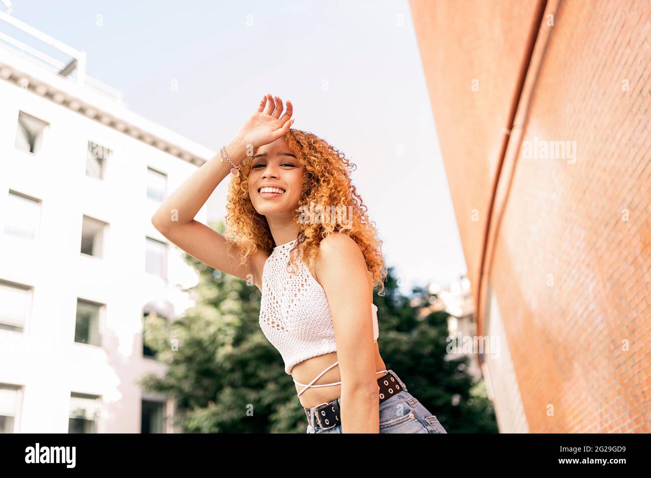 Photo de stock de portrait de jeune fille blonde de la ville. Elle a une attitude confiante et regarde la caméra. Elle porte des vêtements décontractés Banque D'Images