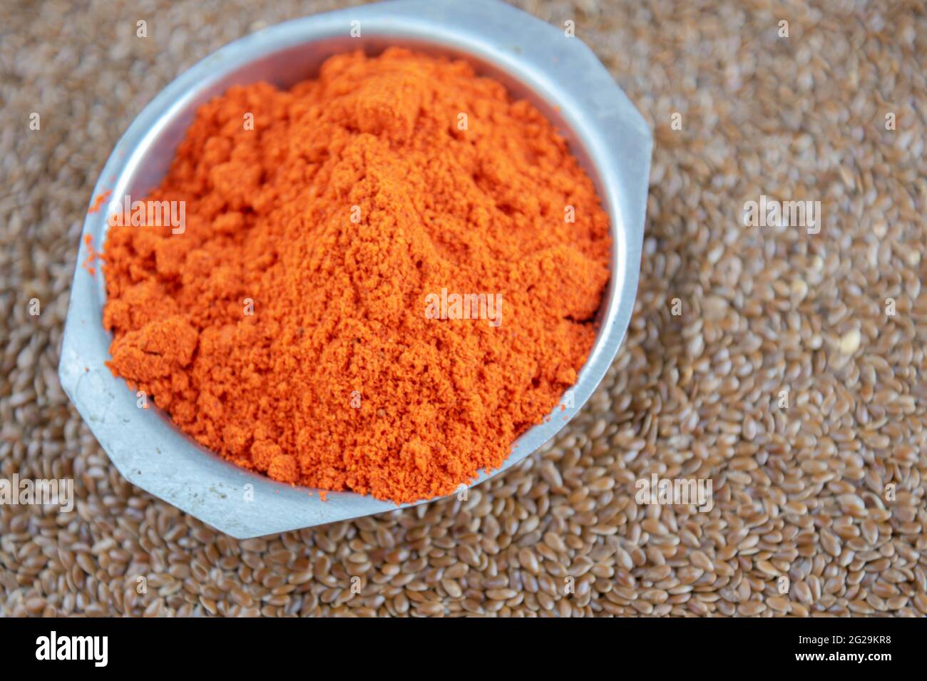 Condiment culinaire de bixa orellana sur graines de lin. L'assaisonnement à l'annatto, également appelé paprika, est courant dans les recettes culinaires européennes. Épices et assaisonnement Banque D'Images