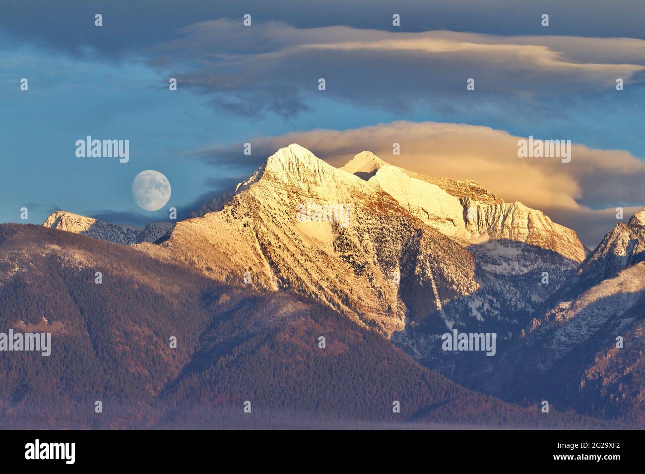 Lune qui s'élève au-dessus des sommets enneigés de la Mission Mountain Range dans l'ouest du Montana - PAS photosautée Banque D'Images