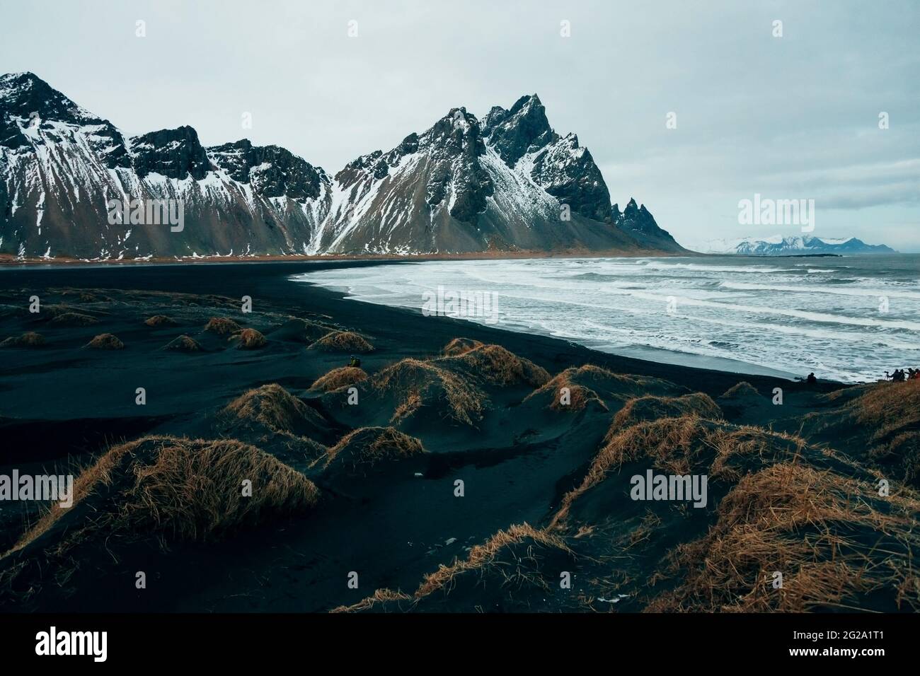 Côte noire vide de l'océan avec des falaises rugueuses dans la neige sous un ciel gris lourd en Islande Banque D'Images