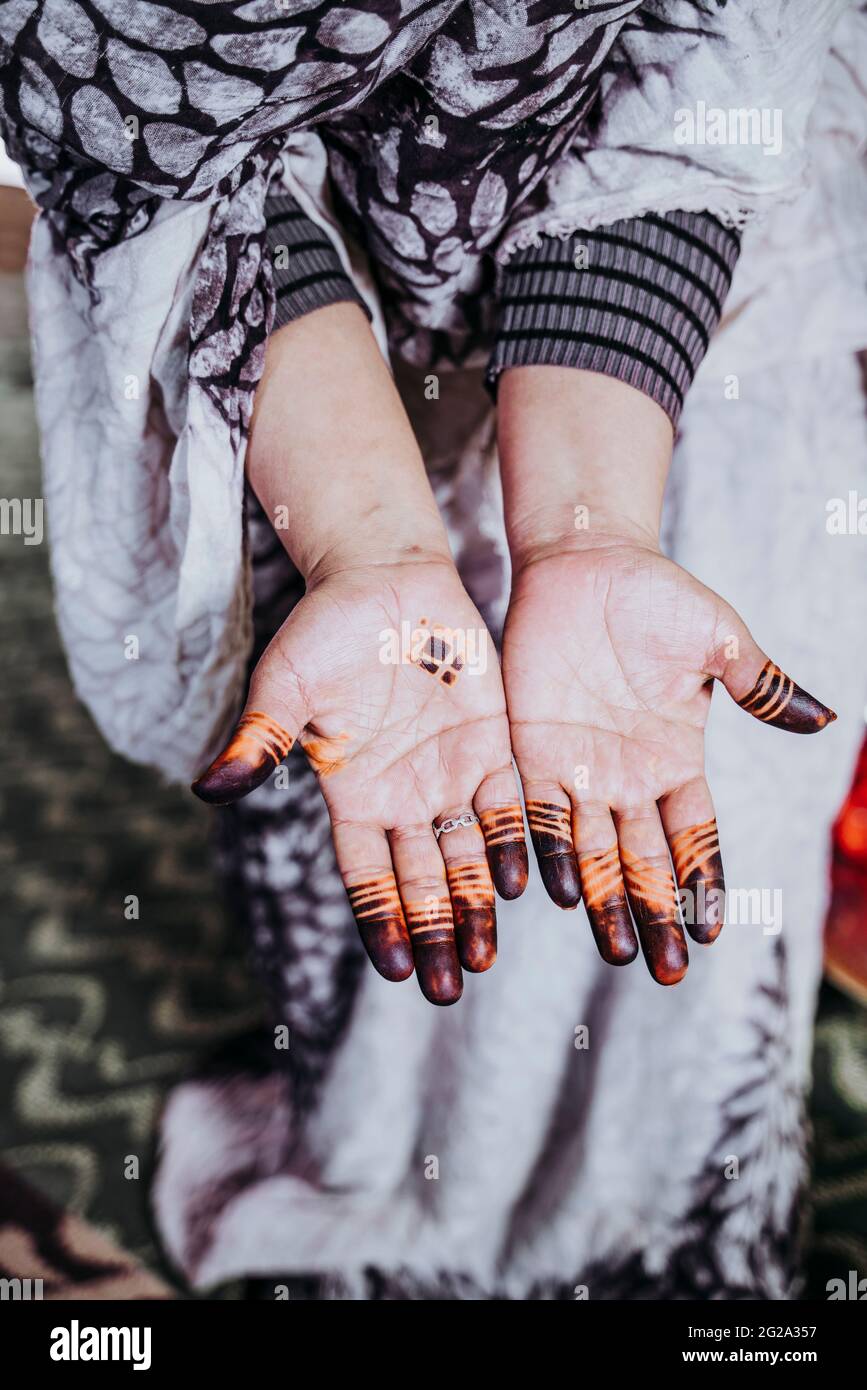Femelle ethnique non reconnaissable dans des vêtements traditionnels montrant des palmiers avec de beaux tatouages ornementaux Banque D'Images