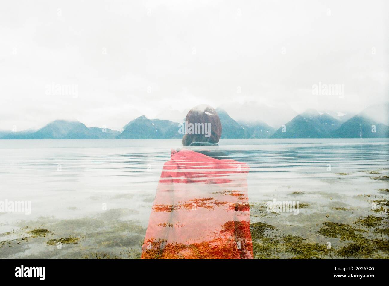 Vue arrière d'un homme en double exposition en chapeau et manteau debout près d'un lac en Laponie Banque D'Images