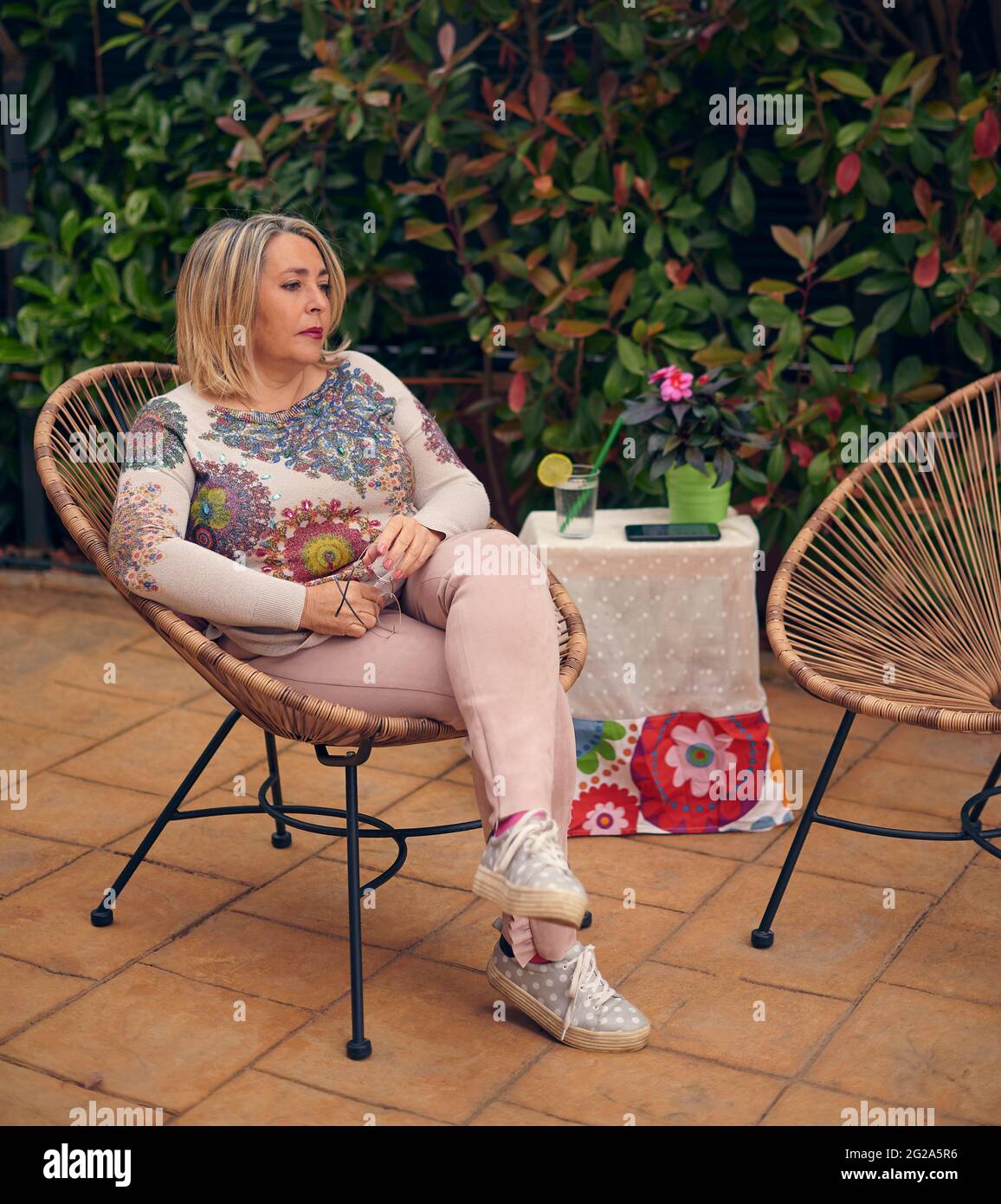 Femme avec téléphone mobile dans son jardin Banque D'Images