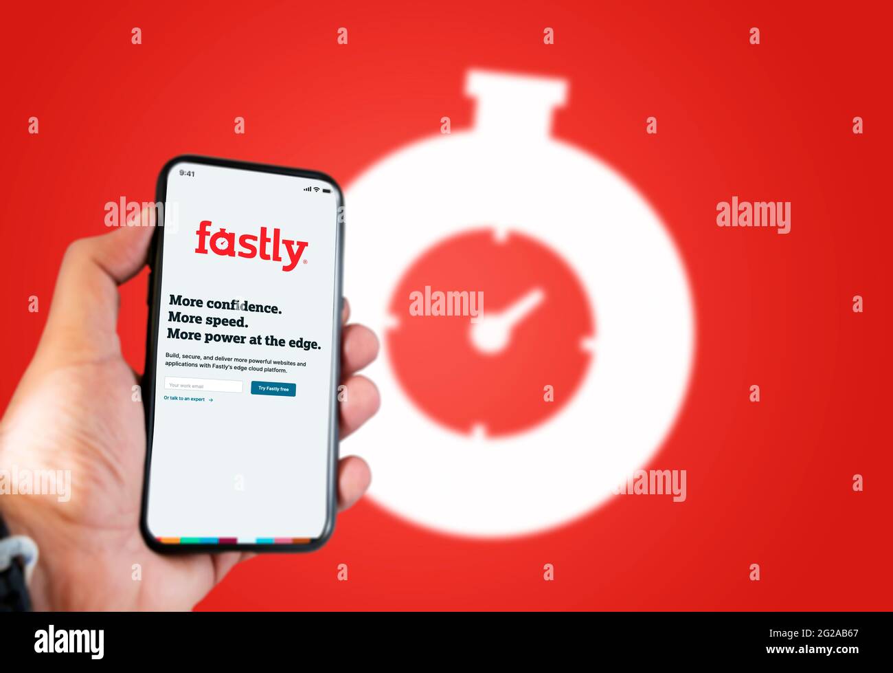 San Francisco, CA, USA, juin 2021: Une main tenant un téléphone avec l'application fastly sur l'écran. Arrière-plan rouge avec logo flou. Fastly est un AME Banque D'Images