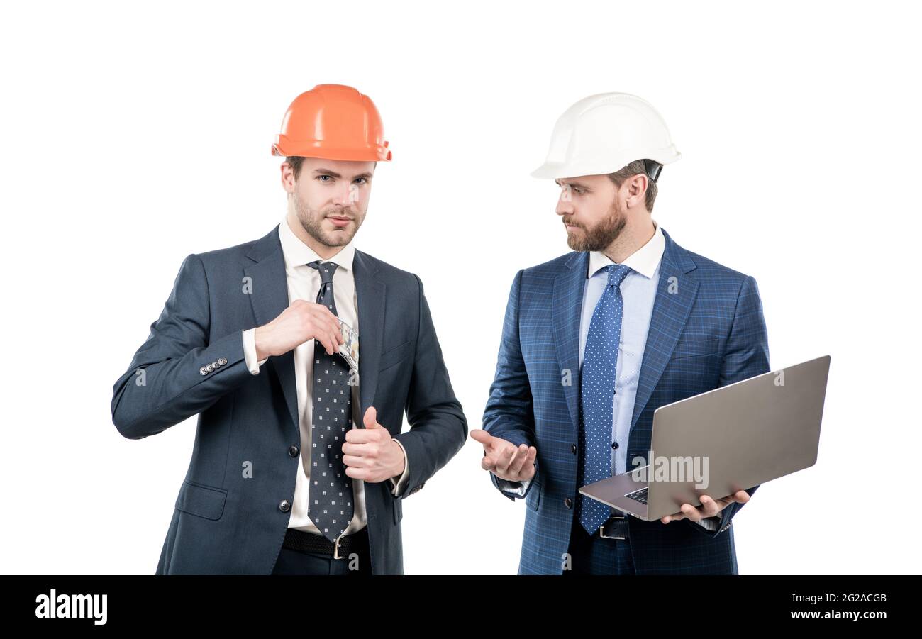 hommes d'affaires en costume et casque de sécurité donnant ou prenant de l'argent et tenant l'ordinateur, pot-de-vin Banque D'Images