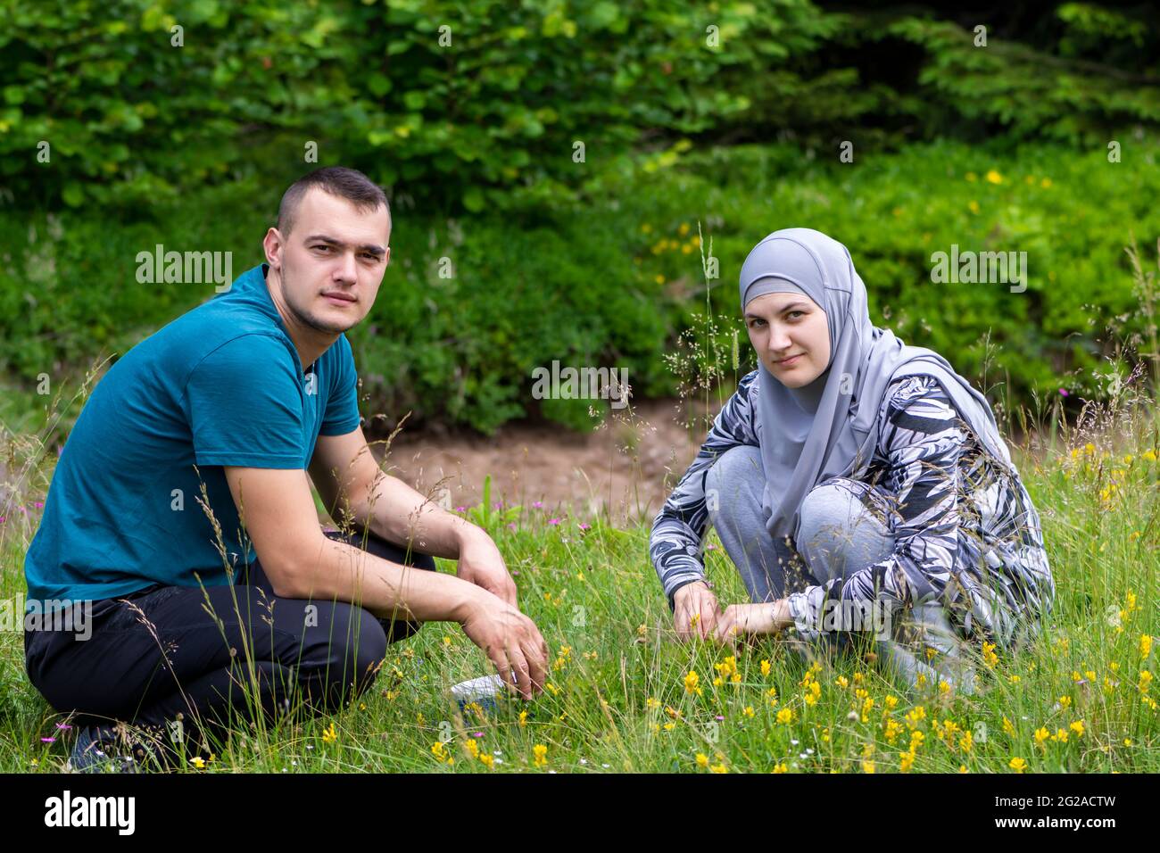 Un jeune couple musulman se squat sur l'herbe et regarde la caméra Banque D'Images