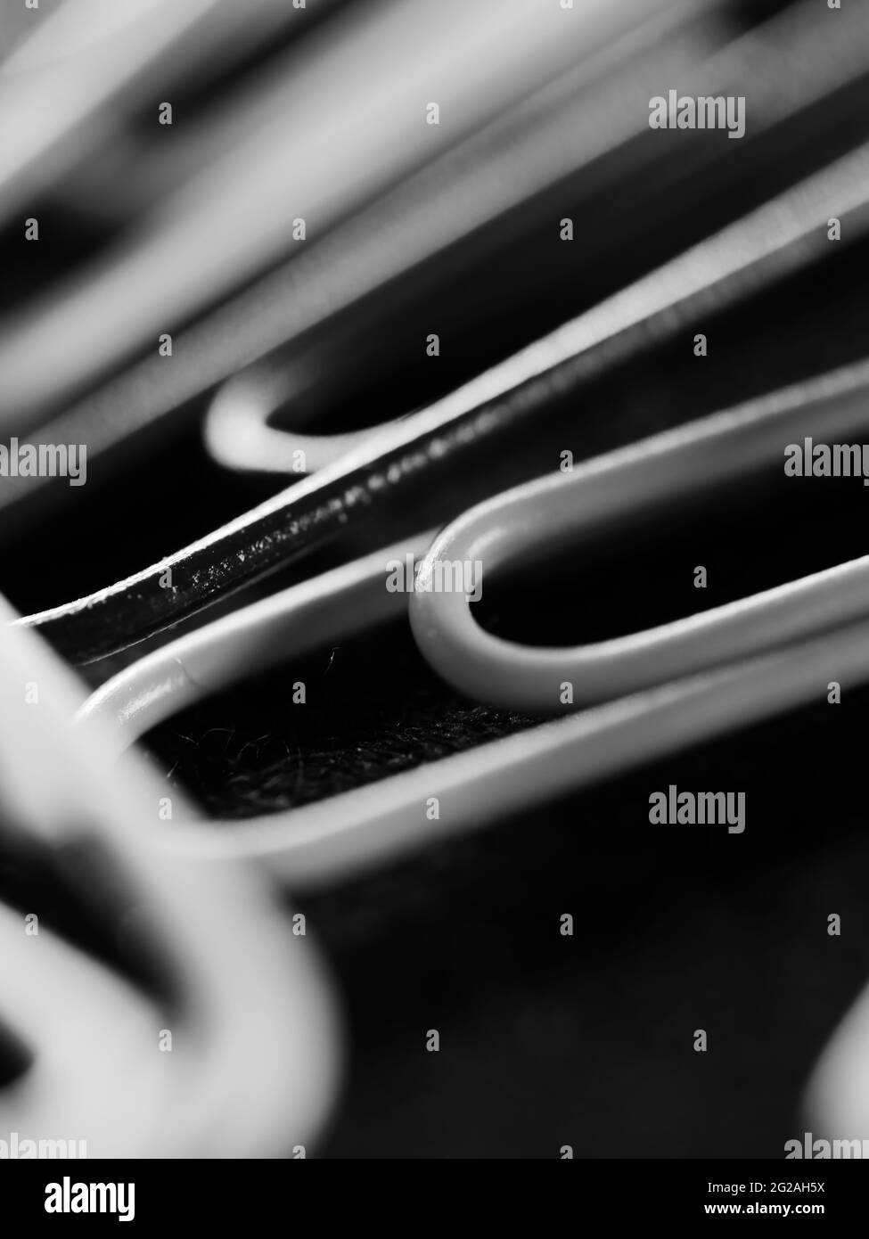 Photo verticale en niveaux de gris de trombones avec lumière floue venant de l'arrière Banque D'Images