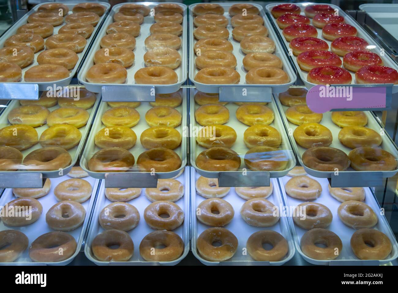 Plateaux remplis de délicieux beignets glacés placés sur une étagère à l'intérieur d'un meuble en verre. Mise au point sélective. Banque D'Images