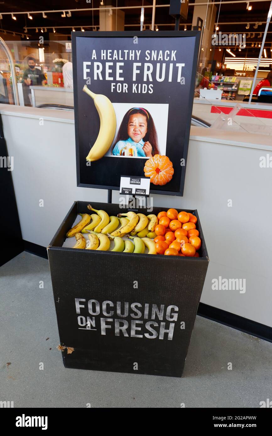 Une corbeille à encas « fruits gratuits pour les enfants » à l'entrée d'un supermarché proposant des fruits pour encourager les enfants à bien manger et à faire des choix sains. Banque D'Images