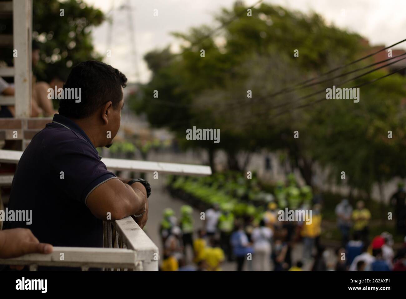 Un homme regarde les manifestants protester tandis que les équipes colombiennes et Argentine jouaient un match qualifiant pour la coupe du monde de Qatar de la FIFA 2022 au stade Metropolitano Roberto Melendez, les manifestations entourant le stade se sont intensifiés et ont été heurtées à des affrontements avec la police anti-émeutes de Colombie contre les troubles et les brutalités policières, à Barranquilla, en Colombie, le 8 juin 2021. Banque D'Images
