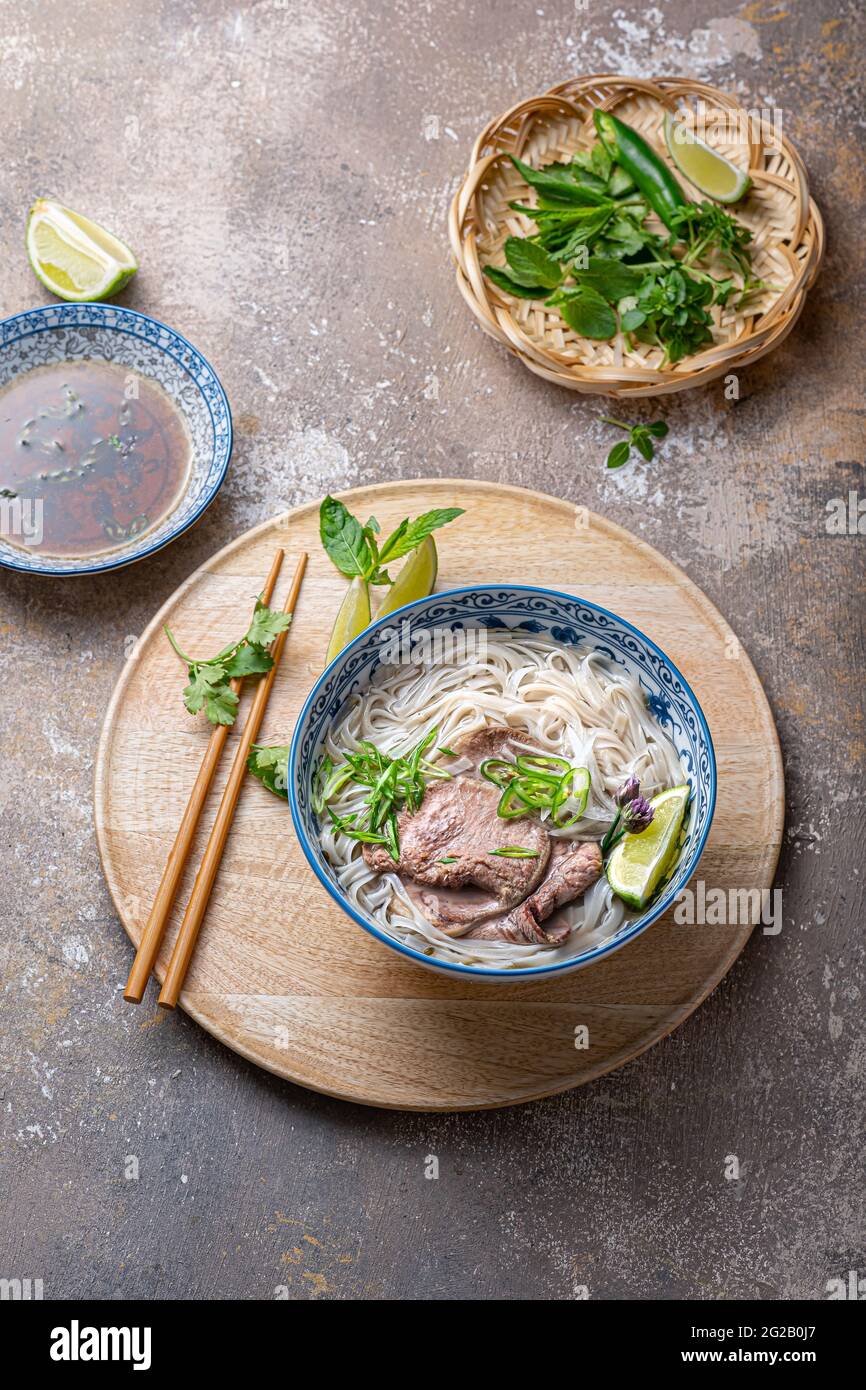 Vue de dessus de la soupe de nouilles de riz vietnamienne de pho bo avec herbes et sauce. Banque D'Images