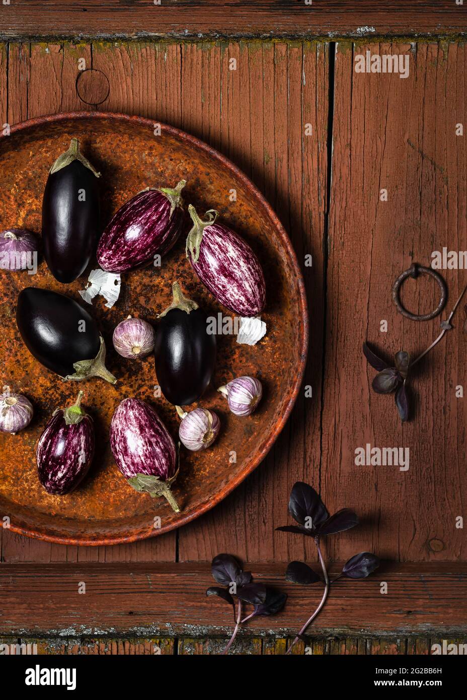 Petits légumes d'aubergine ou d'aubergine à l'ail et feuilles de basilic violets sur fond de bois rustique ancien. Concept de nourriture saine avec espace de copie. Banque D'Images