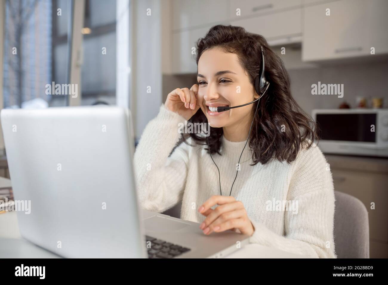 Un opérateur dans des écouteurs assis à l'ordinateur portable tout en travaillant de la maison Banque D'Images